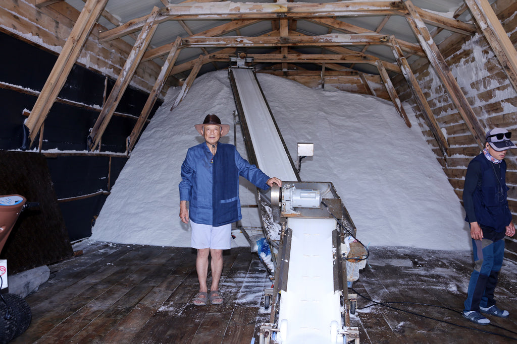 A family member with the salt harvest curing in the storage barn on Imjado